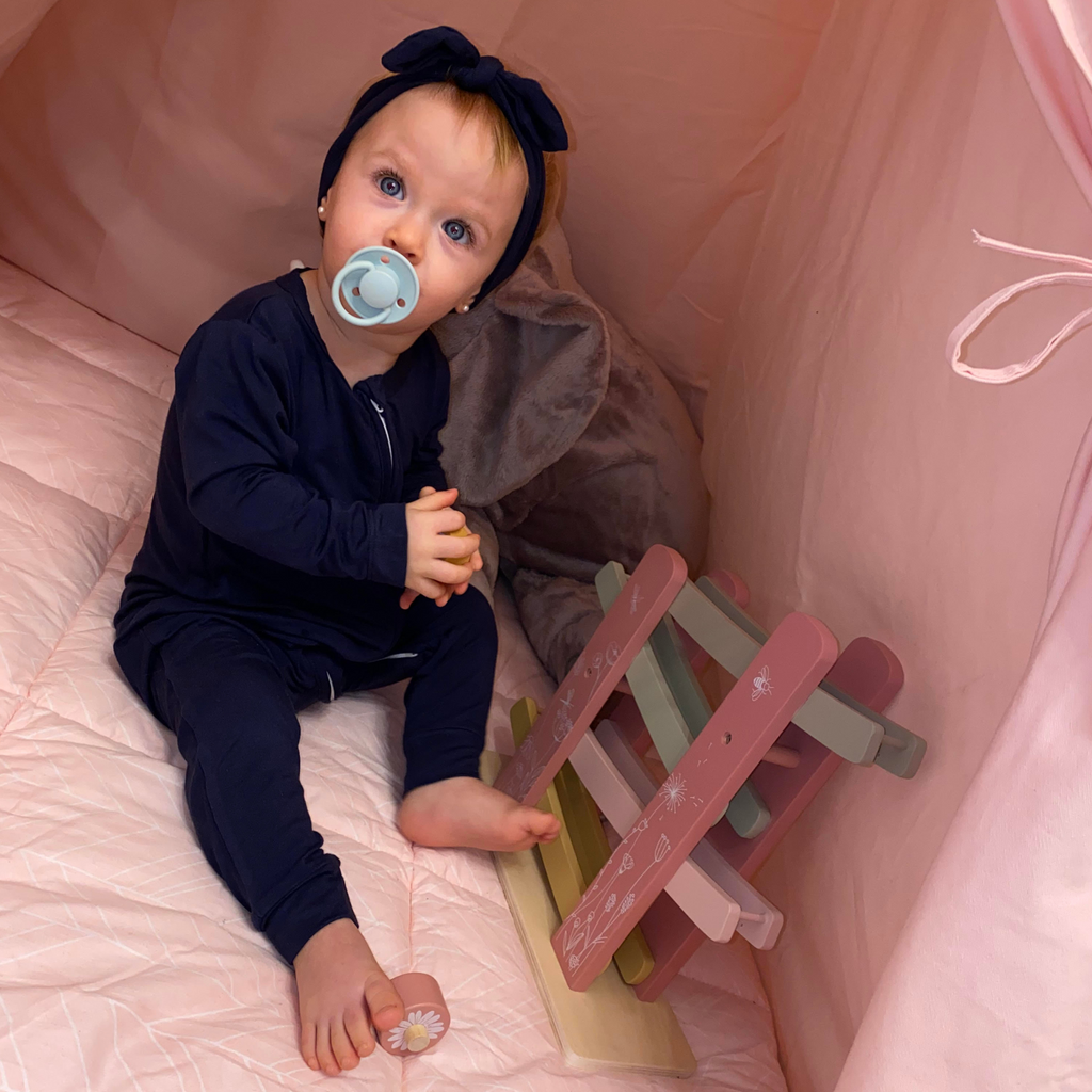 Baby girl palying in LiaaBébé Navy Blue Top Knot Headband and in matching sleepsuit.