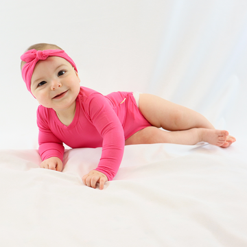 Baby girl playing in LiaaBébé Long Sleeve Bodysuit in hot pink color.