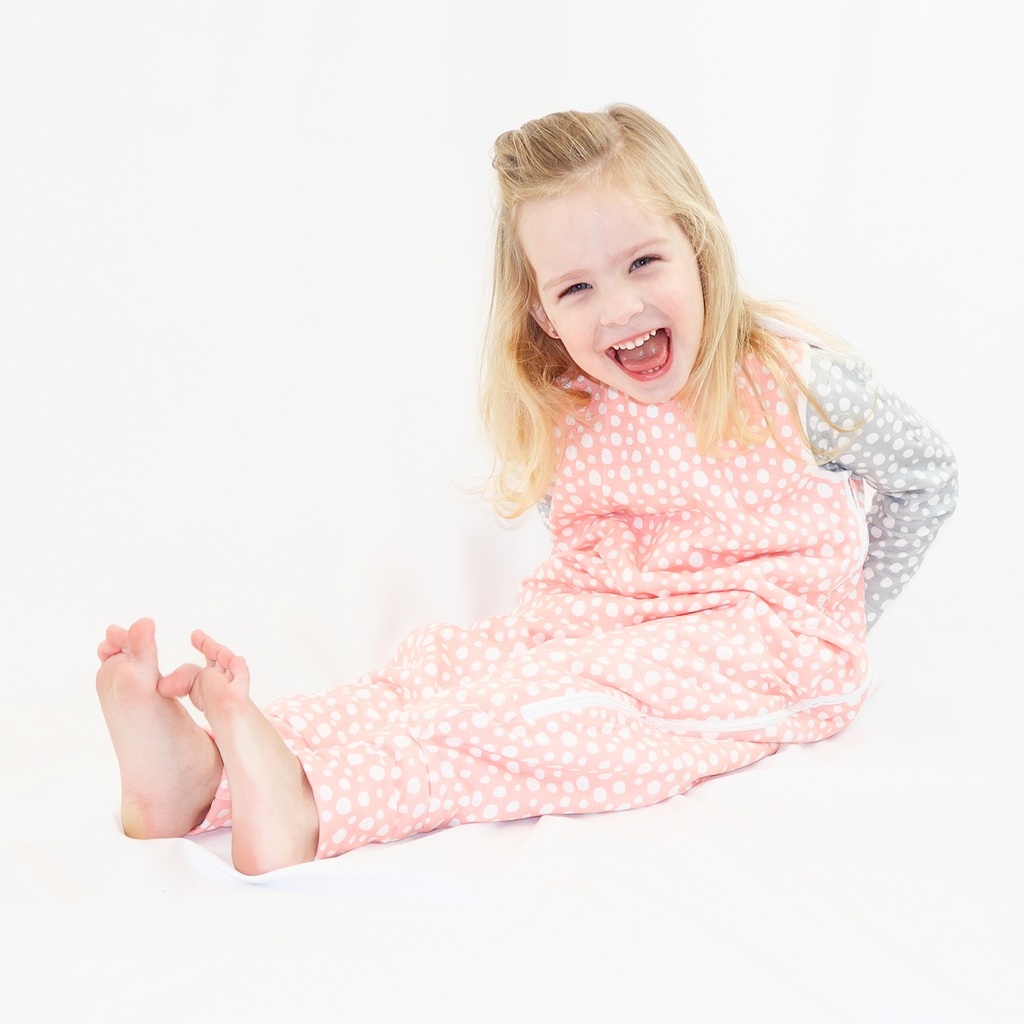 Smiling little baby girl in LiaaBébé Toddler Sleeping Bag in Light Pink color with dots.